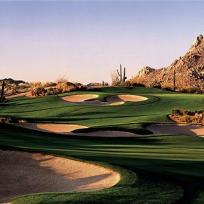 Ein Golfplatz in einer ariden Berglandschaft mit Blick auf felsige Gipfel.