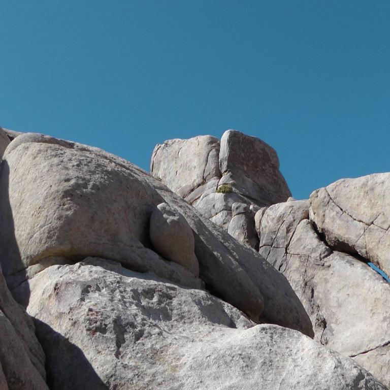Eine Ansammlung großer, heller Felsen vor einem klaren blauen Himmel.