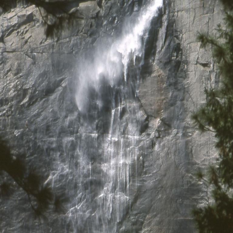 Ein Wasserfall stürzt über eine dunkle, felsige Klippe.