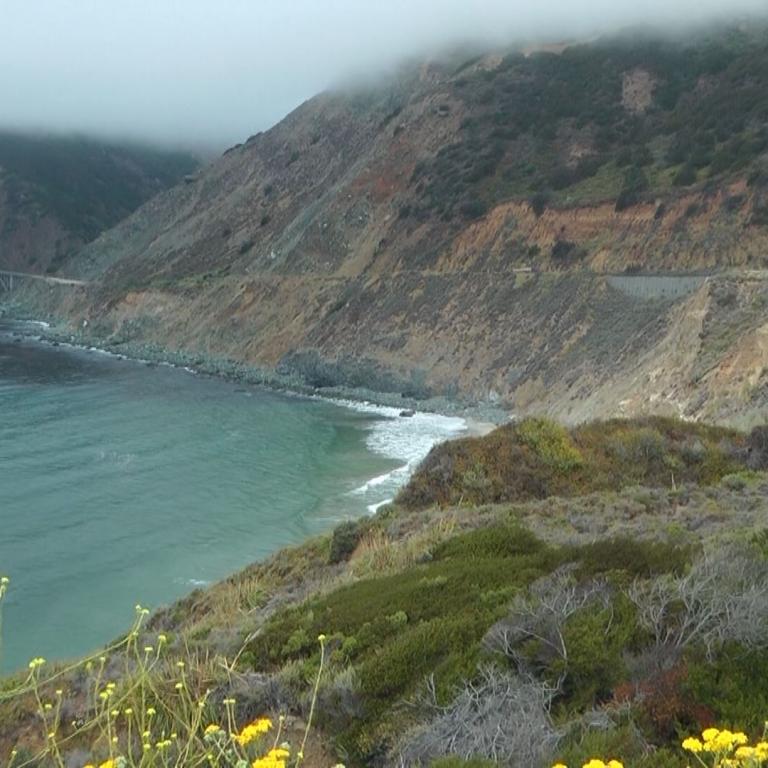 Dramatische Küstenlandschaft mit steilen, nebelverhangenen Klippen, die in das Meer abfallen.