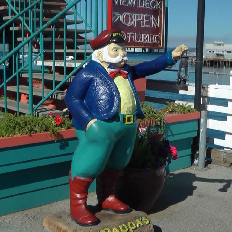 Statue eines Mannes in Uniform auf einem Steg mit Blick auf das Wasser