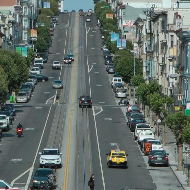 Weitwinkelaufnahme einer städtischen Straßenkreuzung mit Hochhäusern und einem zentralen Fahrstreifen