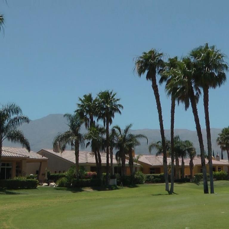Eine Aufnahme eines Resorts mit Palmenreihen, mediterranen Häusern und Blick auf die Berge.