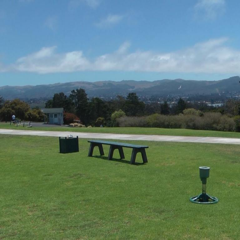 Ein Golfplatz mit Ausblick auf eine weite Hügellandschaft unter blauem Himmel.