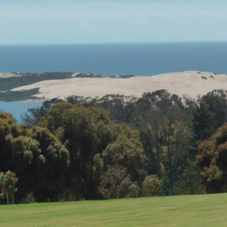 Panoramablick auf eine Küstenlandschaft mit Sanddünen und Meer.