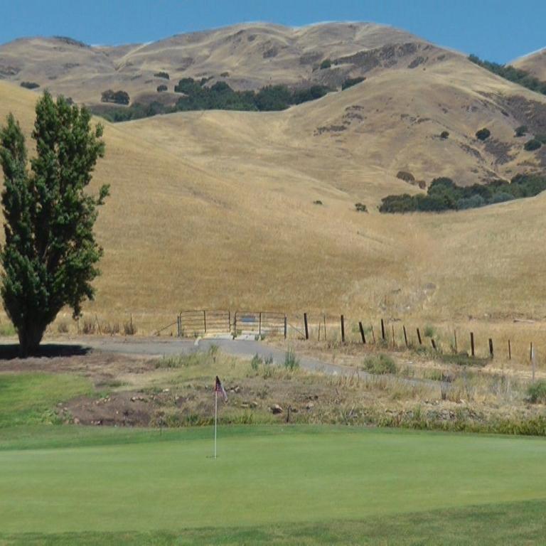 Ein Blick vom Golfplatz auf sanfte, trockene Hügelketten im Hintergrund.