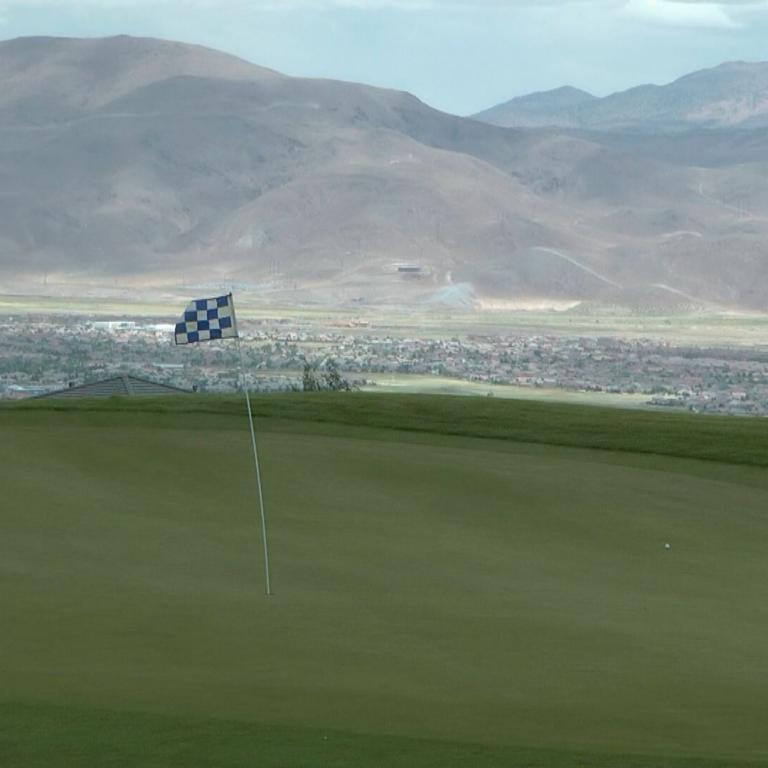 Panoramaansicht eines Golfplatzes mit Blick auf eine Stadt und Bergen.