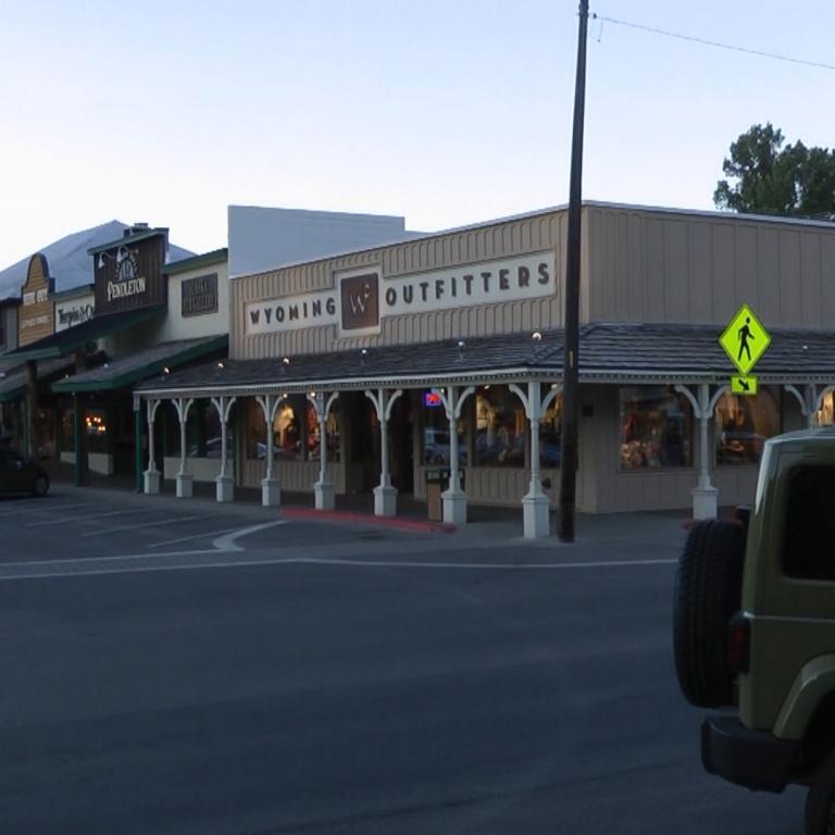 Eine Geschäftsreihe, die Wyoming Outfitters mit einem prominenten Schild zeigt, aufgenommen von einer Straße.