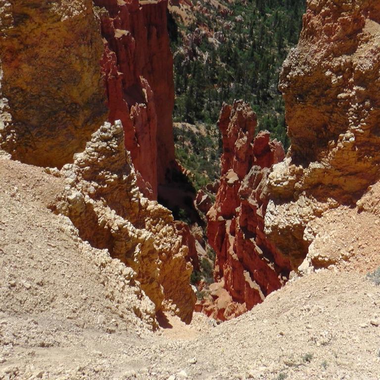 Steil aufragende rote Felsklippen in einer trockenen Wüstenlandschaft.