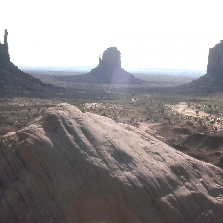 Drei markante Tafelberge oder Buttes stehen in einer weiten, kargen Landschaft