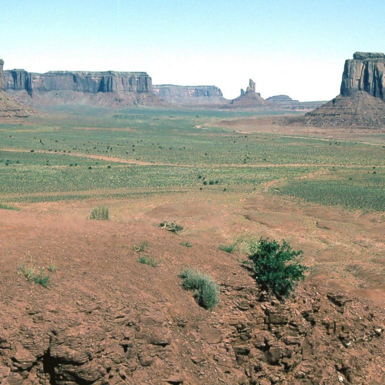 Weitläufige Savannenlandschaft mit markanten, erhabenen Felsformationen im Hintergrund.